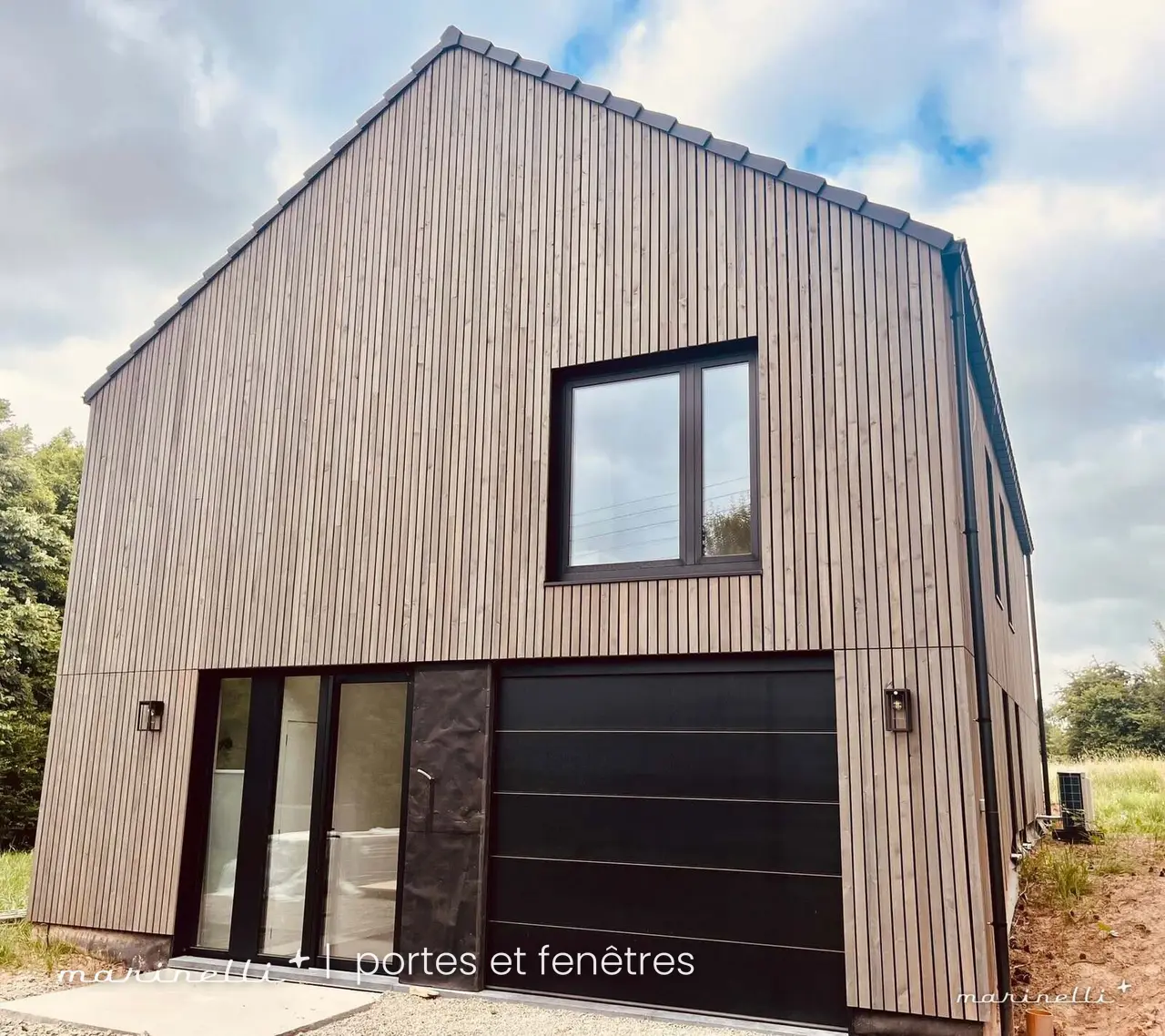 Maison à bardage bois — châssis noirs et porte de garage sectionnelle noire