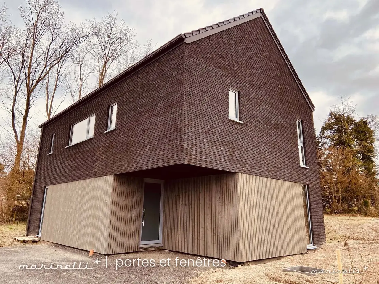 Maison à bardage sombre — Châssis en cours de pose